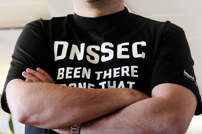 Man står med armarna i kors och har en svart tröja med texten "DNSSEC been there done that".