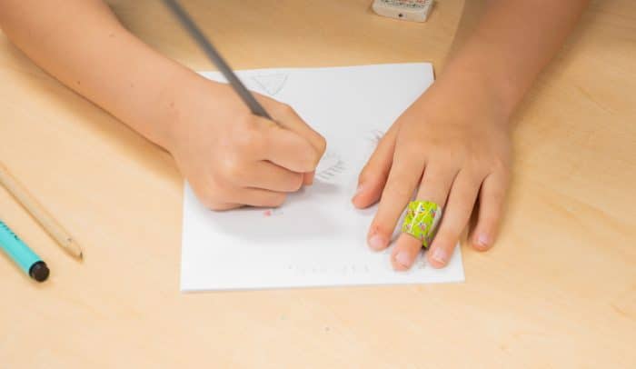 Barnhand med blåster ritar.