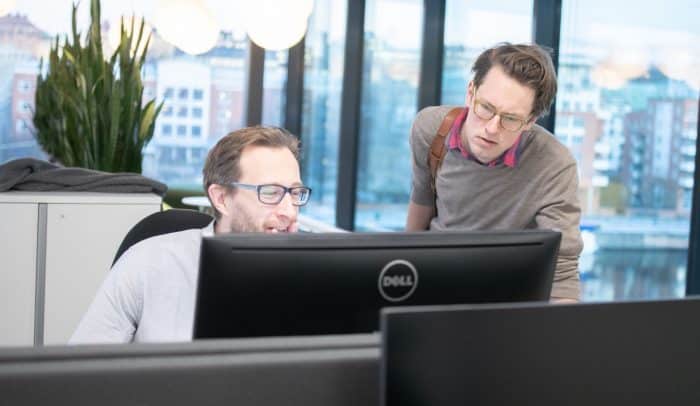 Två män tittar på en datorskärm på kontor.
