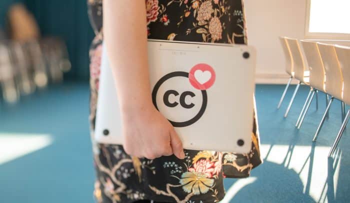 Kvinna bär en laptop med cc-klistermärke