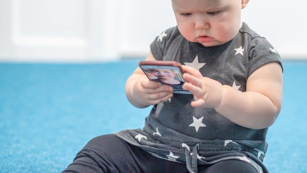 Bebis tittar på en mobiltelefon i handen.
