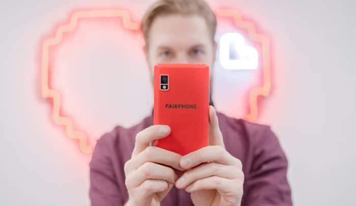 Man håller upp en röd fairphone.