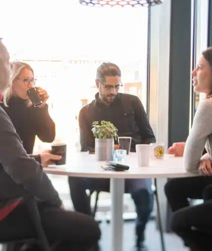 Grupp medarbetare på internetstiftelsen konverserar vid bord.