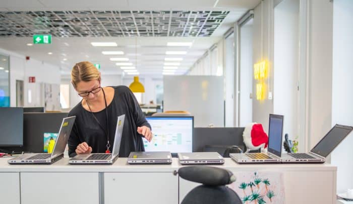 Kvinna inspekterar datorer i kontorsmiljö.