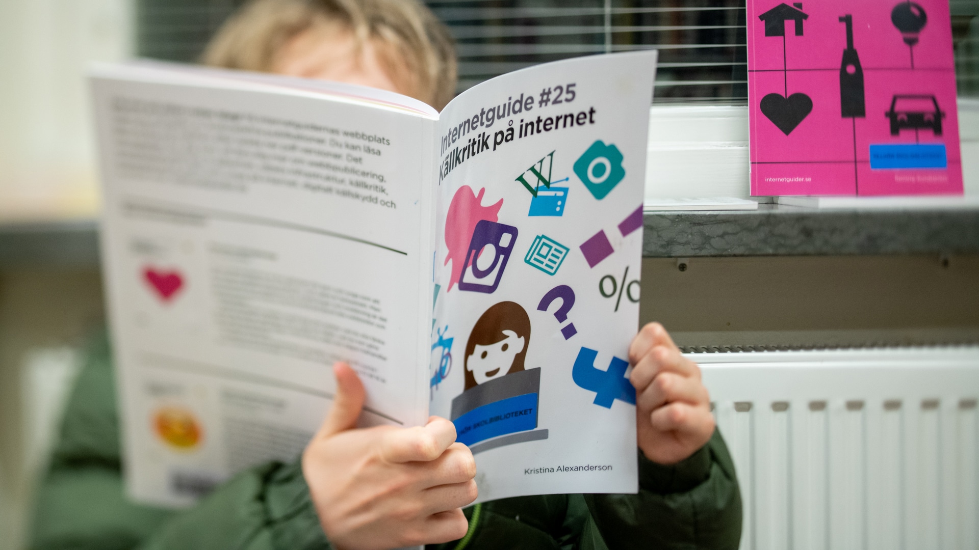 Ett barn sitter och bläddrar i Internetstiftelsens internetguide Källkritik på internet