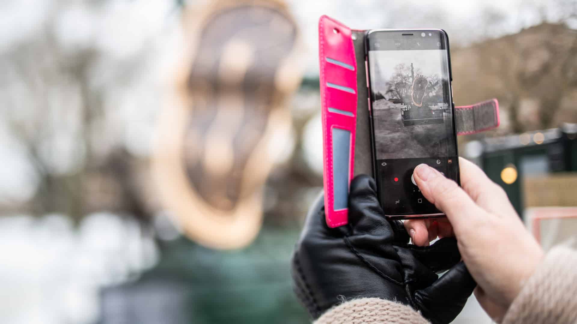 Händer tar foto med en mobil utomhus.