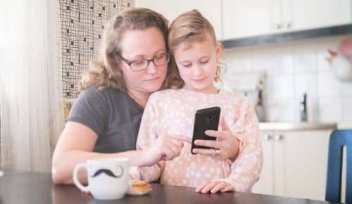 Förälder och barn tittar på mobiltelefon.