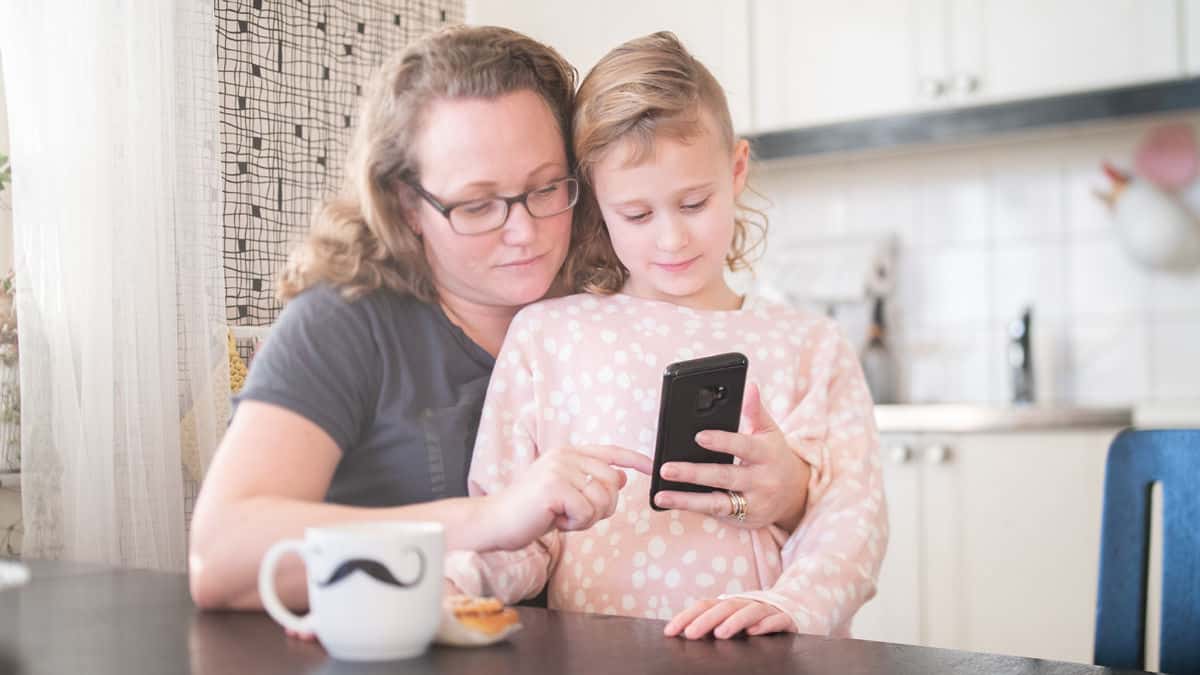 Förälder och barn tittar på mobiltelefon.