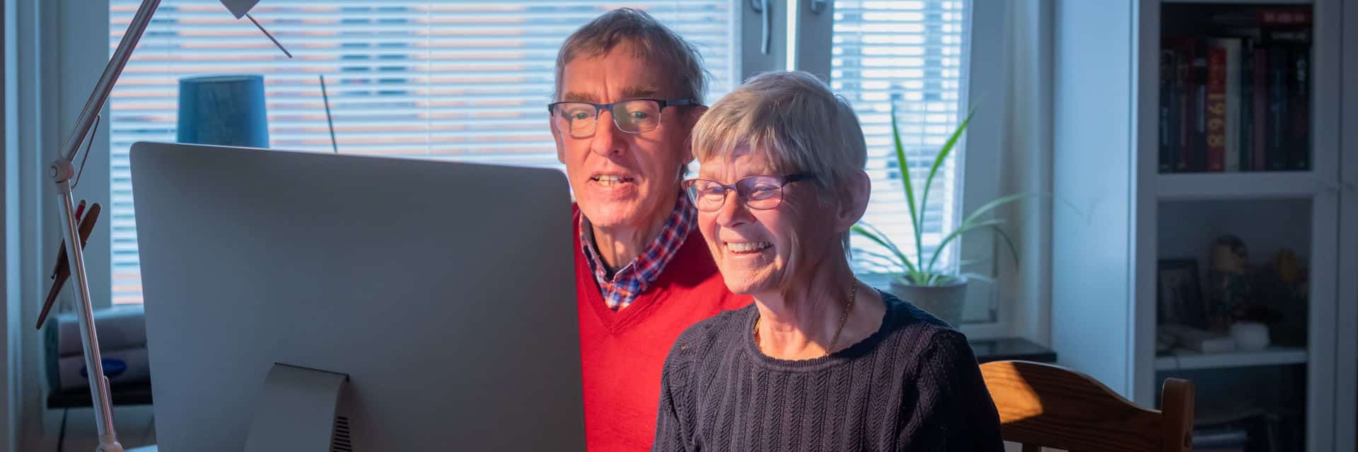 Äldre par sitter framför datorn och arbetar tillsammans