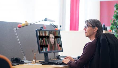 Man som sitter framför en digital föreläsning vid sitt skrivbord.