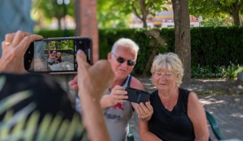 Äldre par med mobiltelefon, fotograferas av annan mobiltelefon.