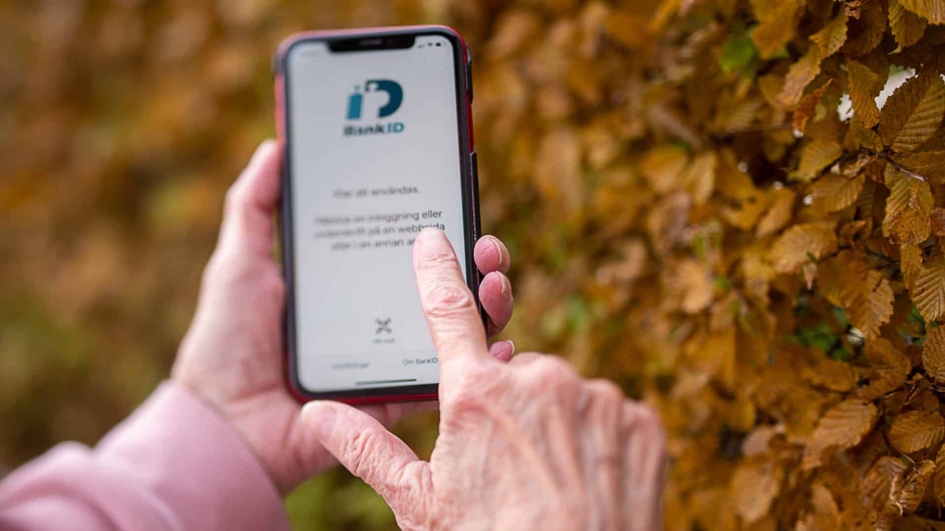 Äldre kvinna använder mobilt bank-id