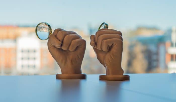 Prispokalen Det gyllene förstoringsglaset, en hand som håller i ett förstoringsglas.