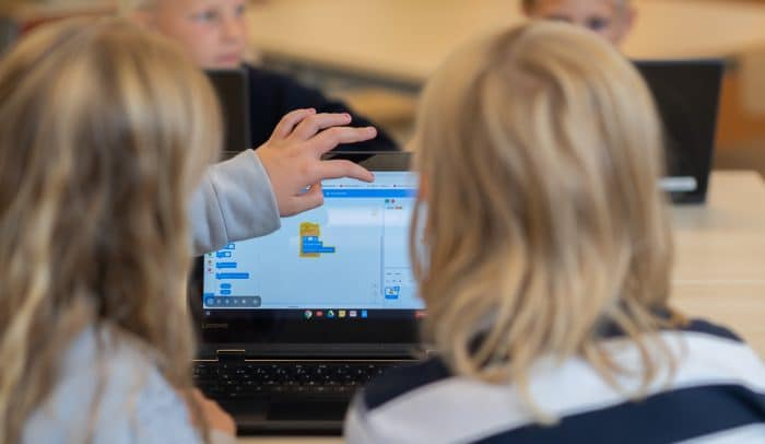Elever sitter i ett klassrum och arbetar med programmeringsverktyget Scratch på en dator.