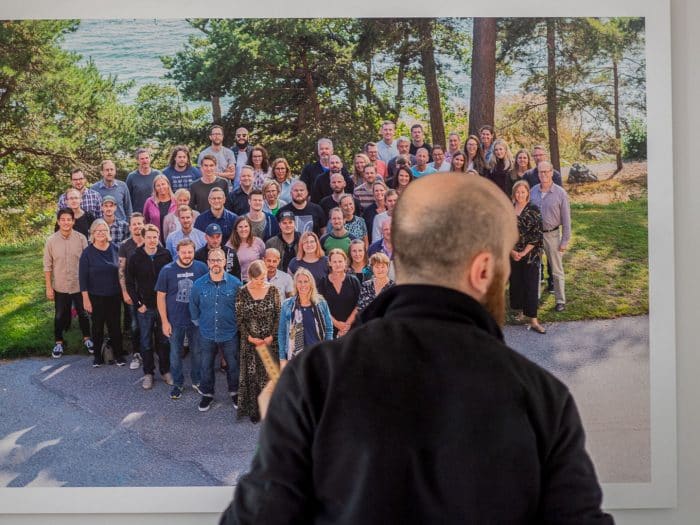 En man tittar på en tavla med anställda på Internetstiftelsen. Medarbetarna står i en hjärtformation.