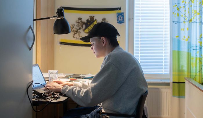 En skolelev sitter vid en bärbar dator i sitt rum