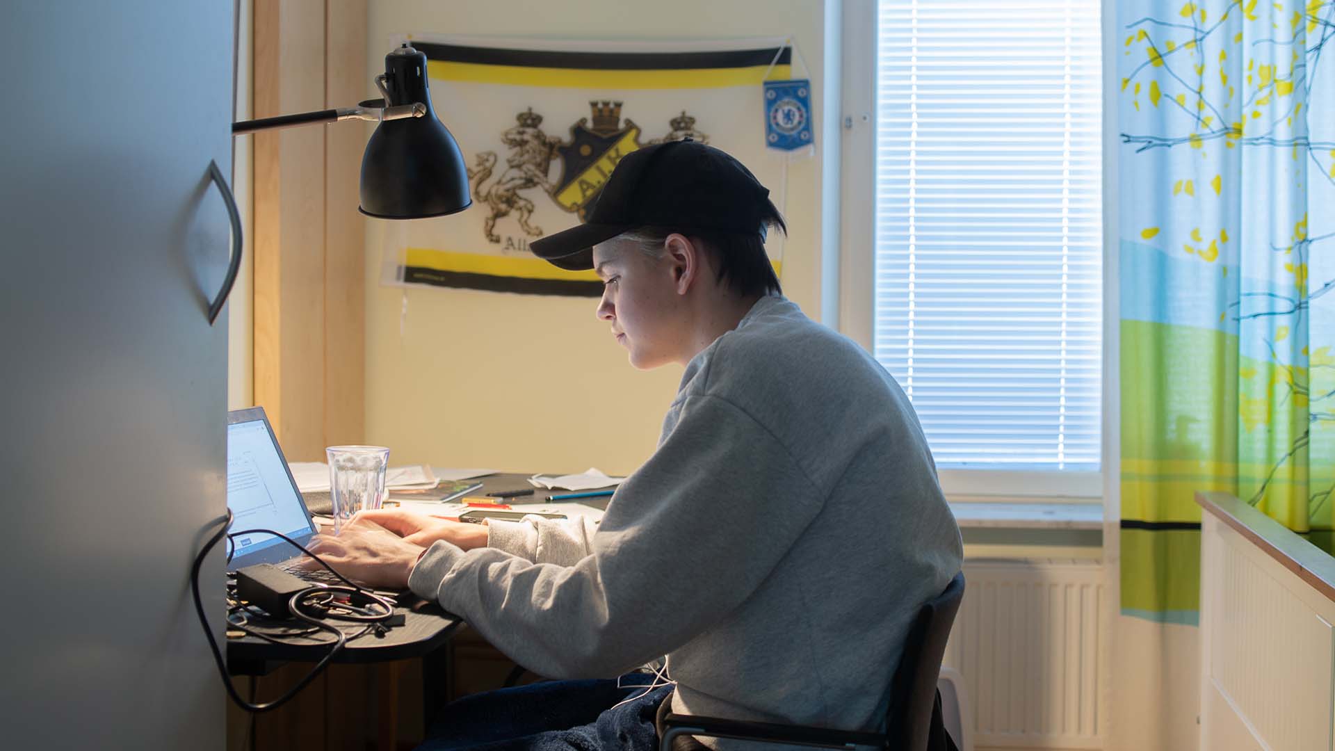 En skolelev sitter vid en bärbar dator i sitt rum