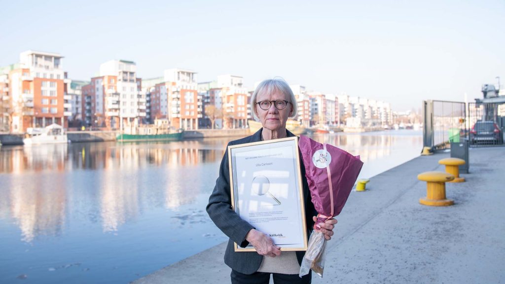 Ulla Carlsson står med sitt pris Det gyllene förstoringsglaset, och diplom vid Hammarbykanalen i Stockholm