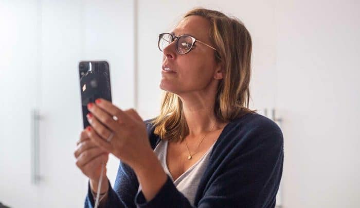 Kvinna med glasögon granskar något på sin mobil.