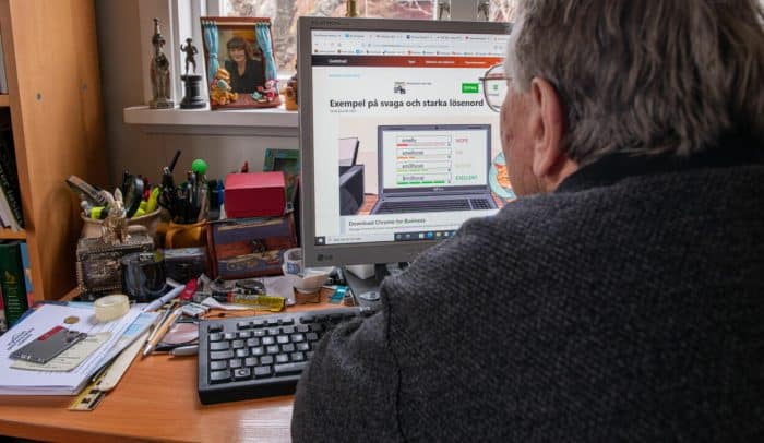 Äldre man sitter framför dator, på skärmen syns en lista över lösenord.