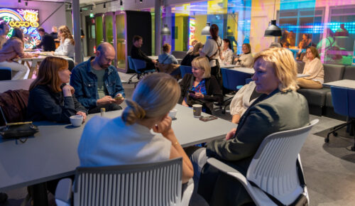 Folk i grupp sitter vid ett bord och arbetar.