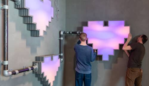 Två personer sätter upp hjärtan i neon på en vägg på Internetstiftelsens kontor.