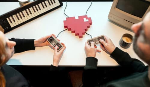 Två personer håller i tv-spelskontroller inkopplade i ett hjärta.