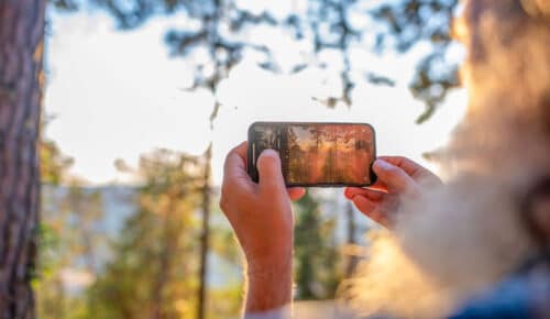 En person tar en bild av en solnedgång med mobilkameran.