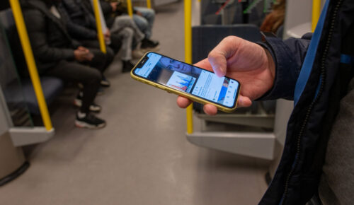 En person står på tunnelbanan och scrollar på mobilen.