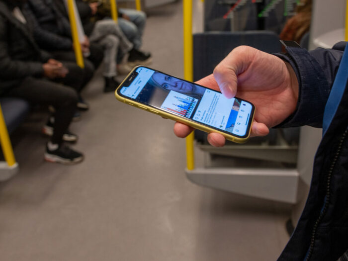 En person står på tunnelbanan och scrollar på mobilen.