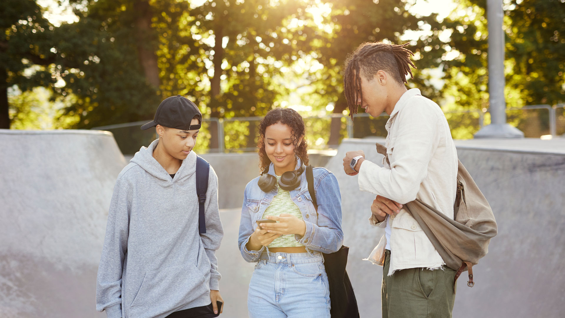 Tre ungdomar tittar på en mobil tillsammans.