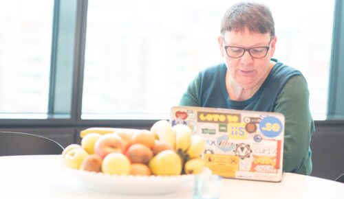 En person som sitter vid ett bord med en tallrik med frukt.