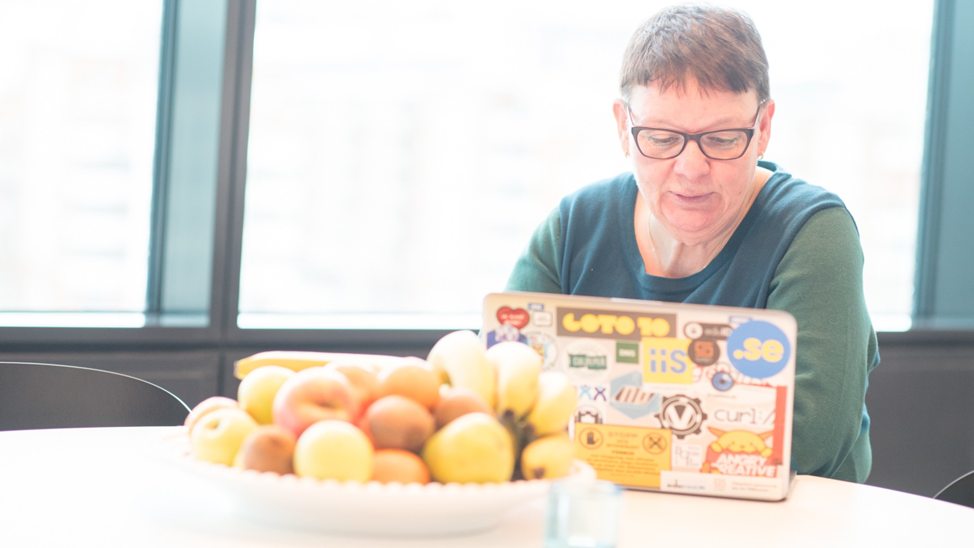 En person som sitter vid ett bord med en tallrik med frukt.