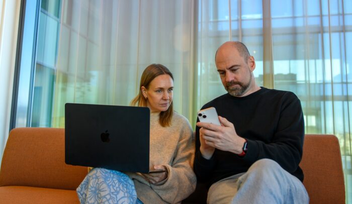 En man och en kvinna sitter i en soffa och tittar på en bärbar dator.