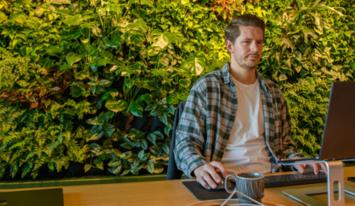 Ung man sitter framför en dator och jobbar.