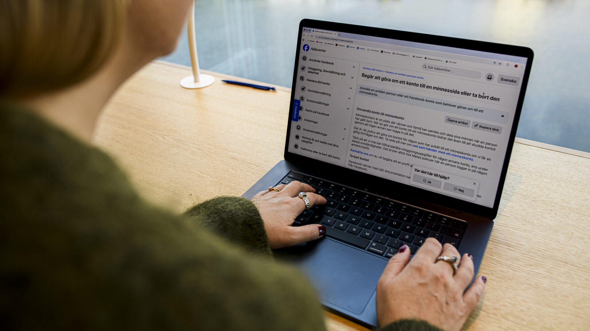 En kvinna sitter framför en dator och kollar upp hur man gör en minnessida på facebook.