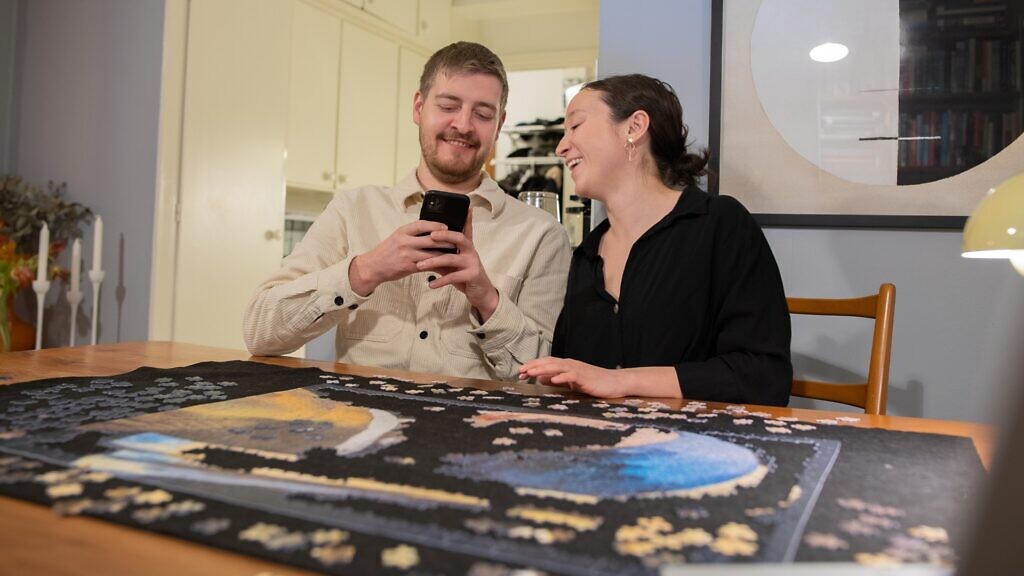 Ungt par har hemmadejt och lägger pussel.