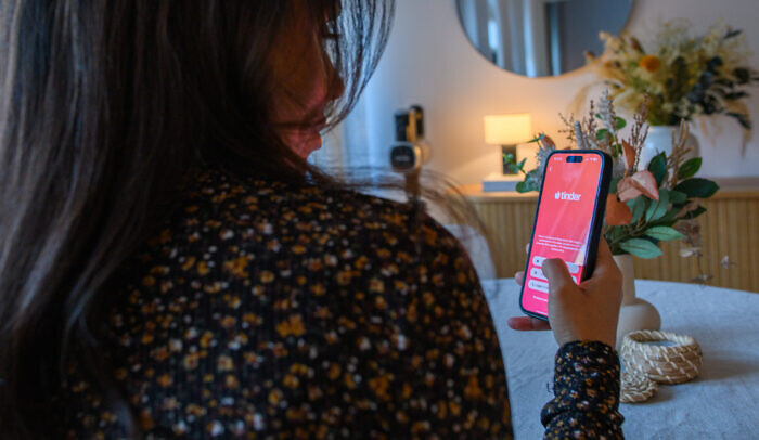 Kvinna som startar Tinder på sin mobiltelefon.