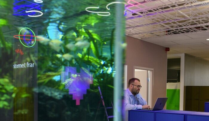 En man står vid ett bord med en laptop, i förgrunden syns ett akvarie.