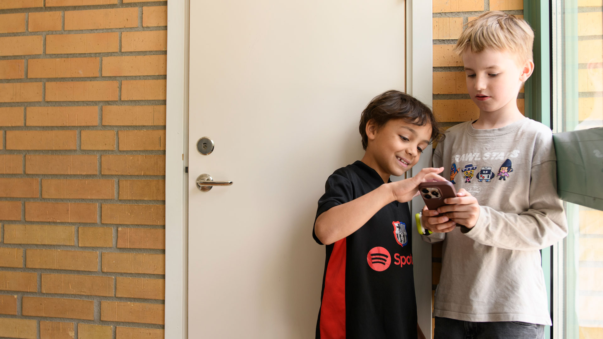 Två barn tittar tillsammans på en mobiltelefon.