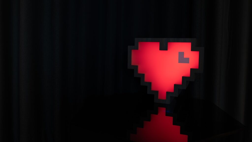 Ett rött lysande pixelhjärta lyser i ett nedsläckt rum.