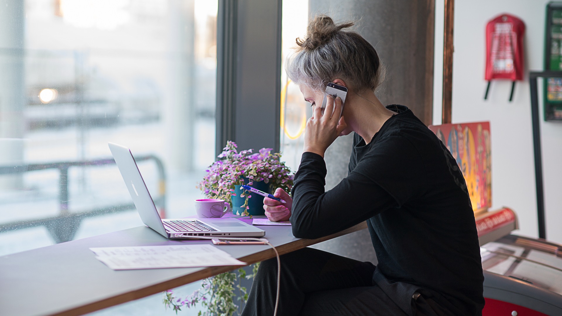 En kvinna sitter vid ett bord och använder en bärbar dator.