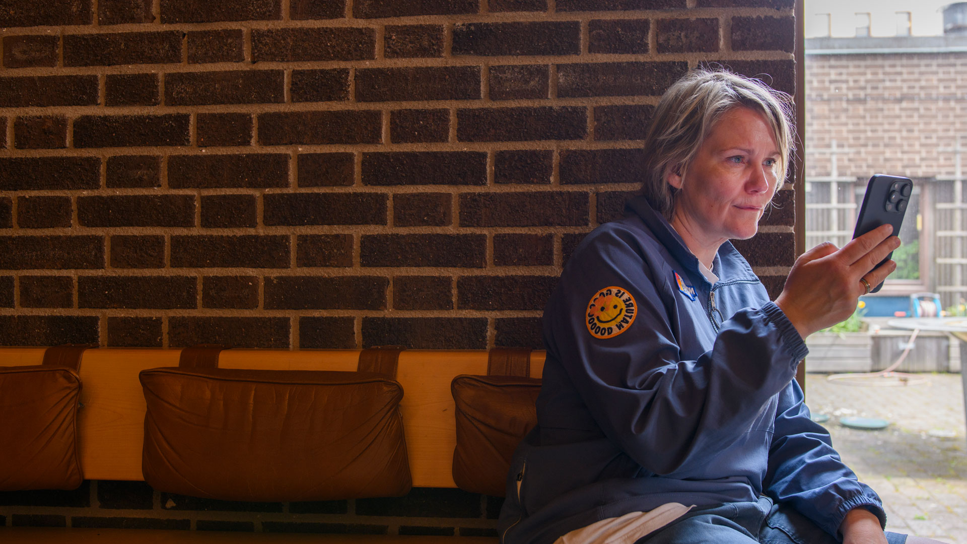 En kvinna sitter på en bänk och tittar på sin mobil.