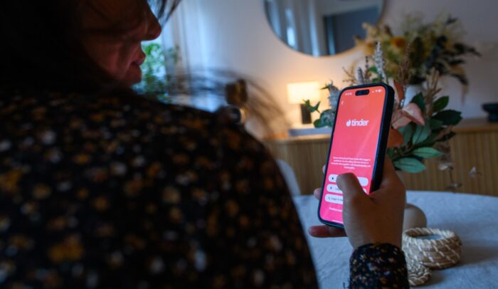 Person håller i mobil med Tinder-appen öppen.