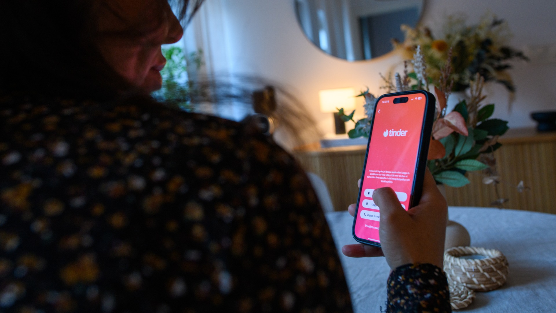 Person håller i mobil med Tinder-appen öppen.