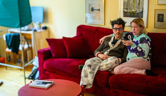 En man och en kvinna sitter i en röd soffa och pratar politik.