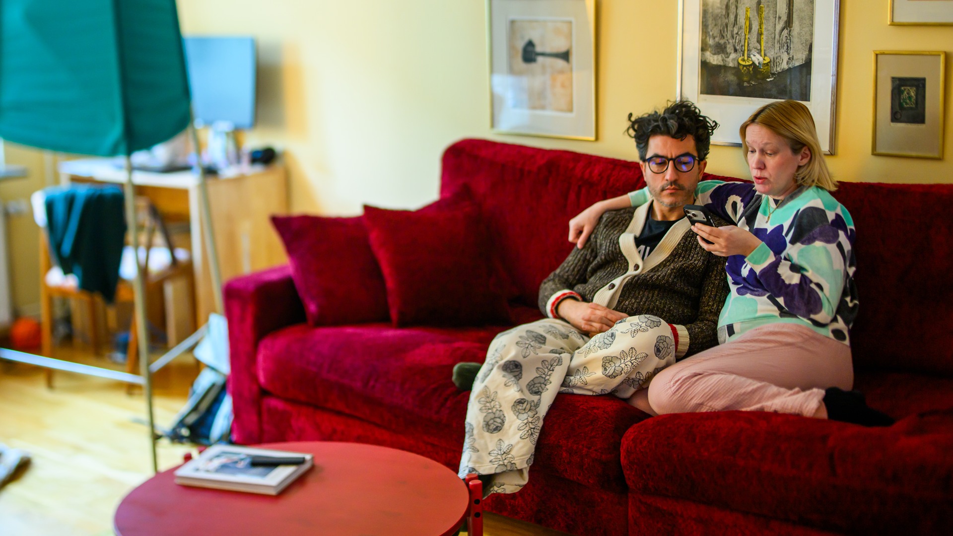 En man och en kvinna sitter i en röd soffa och pratar politik.