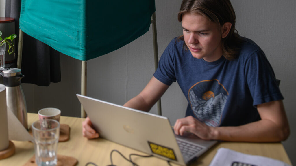 Ung man sitter framför en dator och hämtar politisk information.