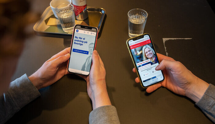 Två mobiltelefoner som visar två olika politiska annonser.