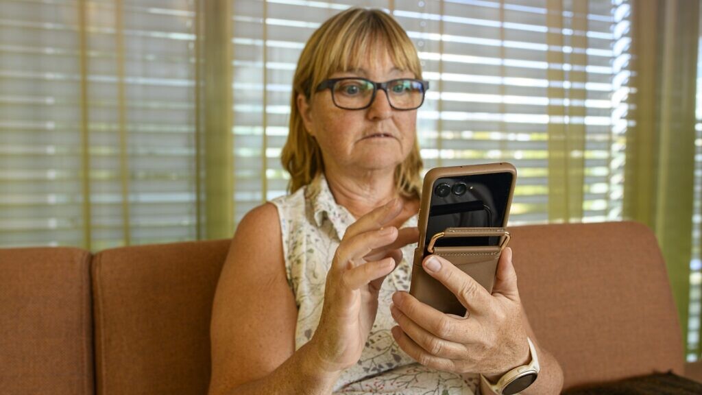 Kvinna sitter i en soffa och använder sin mobiltelefon.
